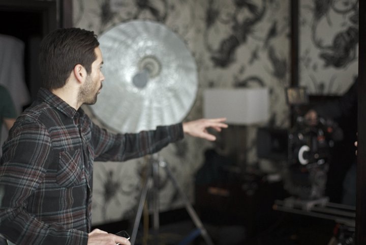 Jonathan R. Whittaker directing on set, gesturing toward a reflector with the camera rig visible.